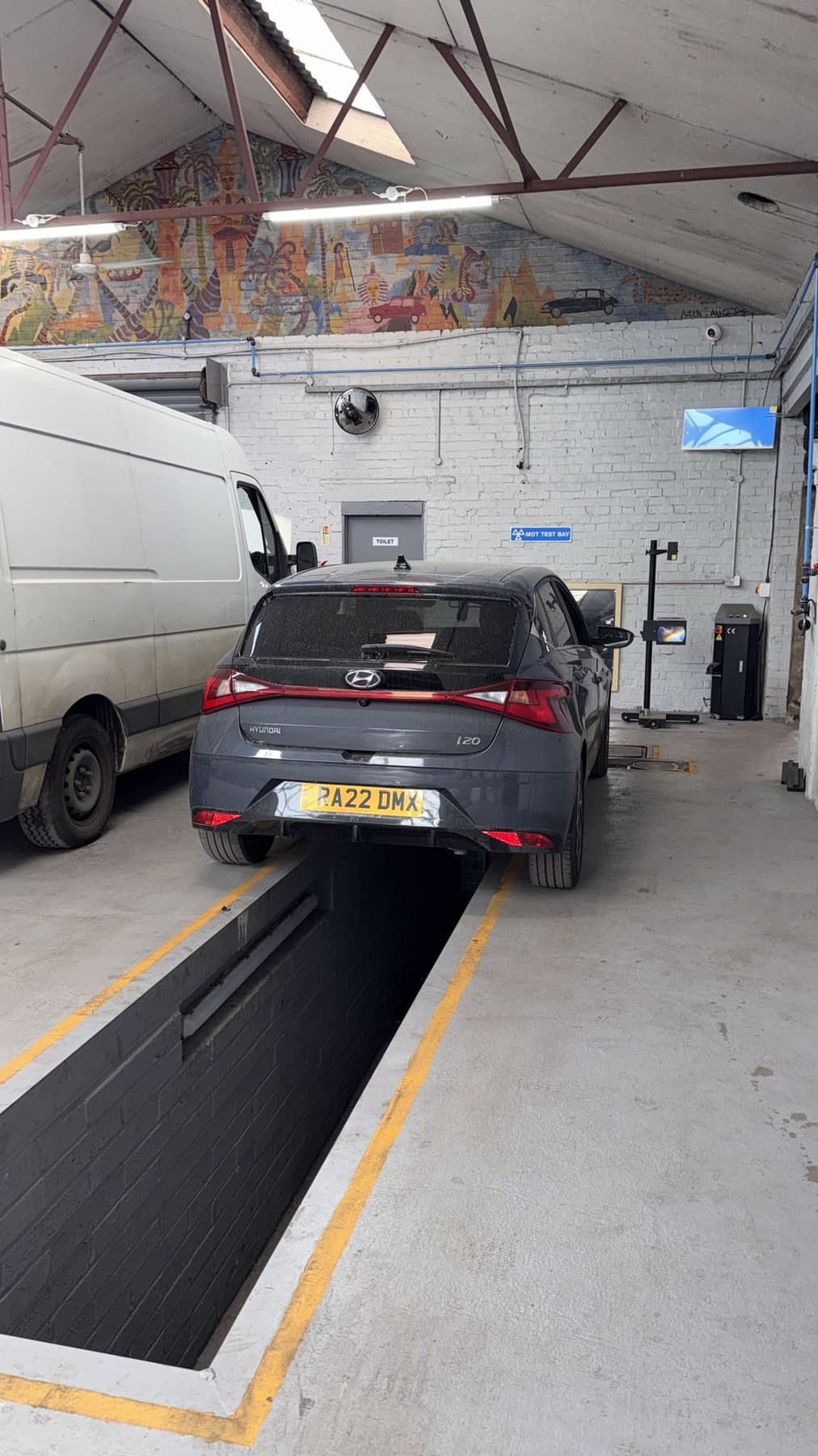 MOT test bay inside the workshop with a car positioned over the inspection pit