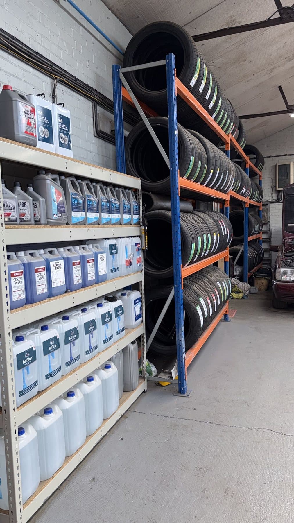 Shelving stocked with engine oil, screen wash and AdBlue beside racked tyres